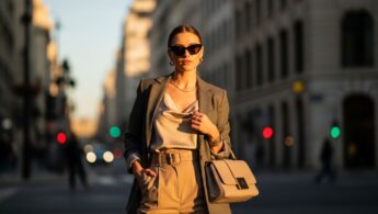 Mladá žena na ulici mesta počas zlatého hodiny s módnymi okuliarmi a kabelkou
